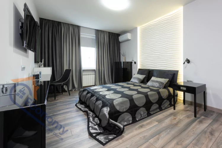 A modern bedroom with a black and white color scheme, featuring a bed with a polka-dot comforter, a black dresser, and dark gray curtains.