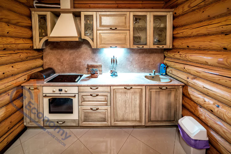 Cabin interior design showing a kitchen with a cozy, rustic feel, including log walls, warm lighting, and traditional cabinets with frosted glass panels and antique hardware.