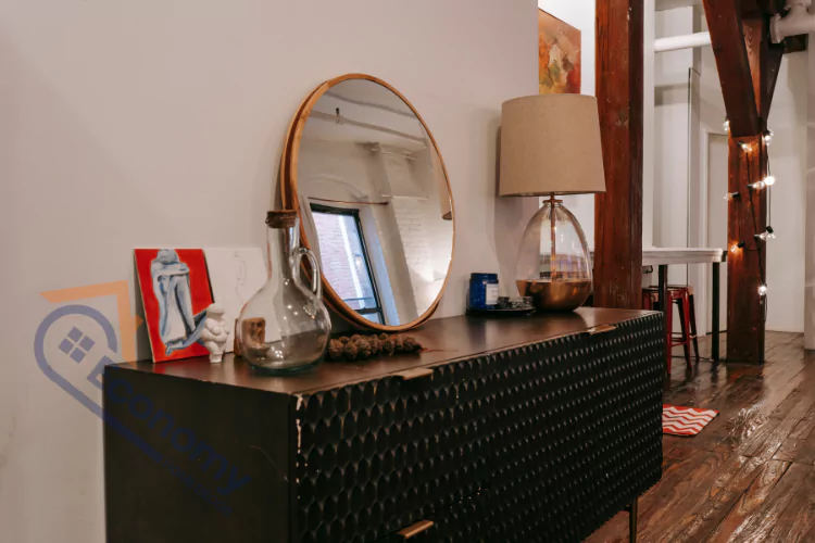 An image showcasing "Dresser Decor Ideas," featuring a black textured dresser adorned with an assortment of objects, including a large mirror and a lamp, creating a chic, personalized look.