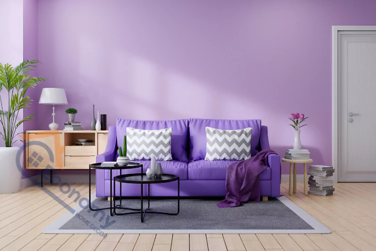A purple-themed living room with a large sofa, two minimalist black tables, and a small side table with stacked books, showcasing a coordinated and modern design.