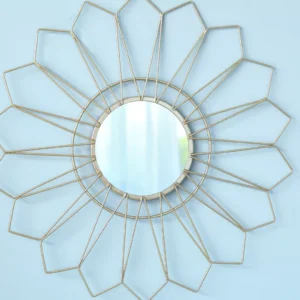 Geometric gold sunburst wall mirror with a round central mirror on a light blue wall.