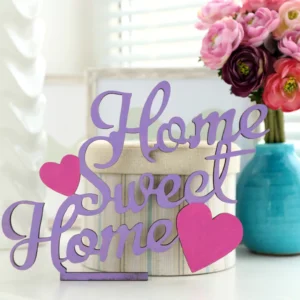 "Home Sweet Home" decorative wood sign with purple lettering and pink hearts on a white table.