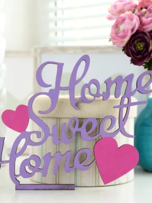 Home sweet home "Home Sweet Home" decorative wood sign with purple lettering and pink hearts on a white table.