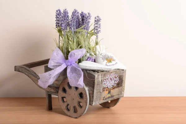 Rustic wooden wagon decor filled with faux lavender and two white lavender sachets, accented with a purple bow.