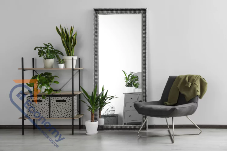 A modern room featuring a large, ornate silver-framed floor mirror leaning against a light gray wall.
