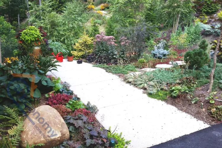 Beautiful Asheville landscape design featuring a stone walkway surrounded by lush greenery, colorful plants, and well-maintained garden beds in a peaceful outdoor setting.