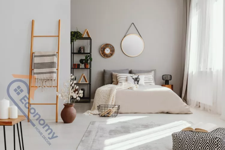 A cozy, light-filled bedroom featuring a natural wood blanket ladder against a gray wall, holding a fringed, striped throw.