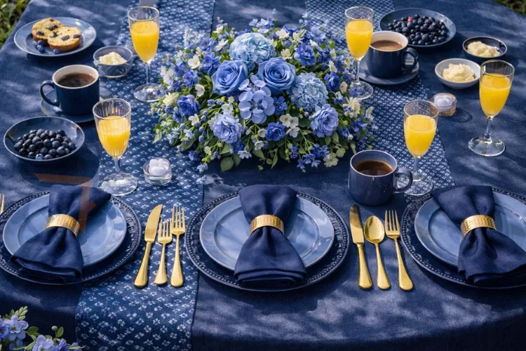 Monochromatic navy brunch table setting featuring varied blue tones in linens and flowers with gold flatware