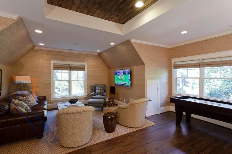 A spacious attic bonus room used as a game and TV lounge, featuring a shuffleboard table and comfortable seating.