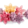 Colorful Modular Origami Paper Decoration A collection of seven handmade paper flowers in various shades of pink, peach/orange, and lavender/purple. The flowers are origami or folded paper creations with multiple petals and detailed centers, displayed on a white background. They look like they could be used for home decor, crafts, or decoration.