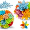 Colorful Modular Origami Paper Decoration Set Set of colorful modular origami paper decorations, including a large sphere, a flower cluster, and an individual flower, with a blue frosted pine branch.