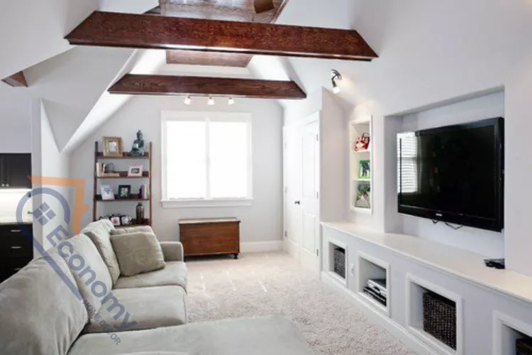 A contemporary attic bonus room converted into a media and lounge space with sloped white walls and exposed wooden ceiling beams.
