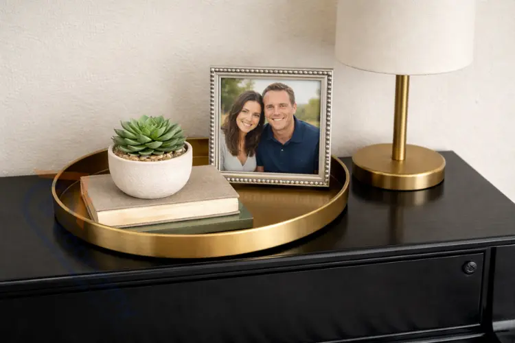 Piano top decorated minimally with brass tray, succulent plant, and silver-framed family photo on black glossy surface