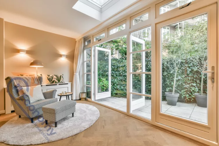A bright sunroom or indoor patio with large French doors demonstrating Lake House Decorating Ideas, leading out to a private courtyard.