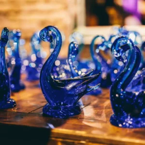 Set of two cobalt blue glass swan figurines with a sparkling, bubbly texture on a wooden surface.