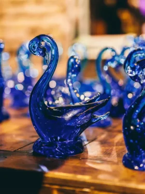 Set of two cobalt blue glass swan figurines with a sparkling, bubbly texture on a wooden surface.