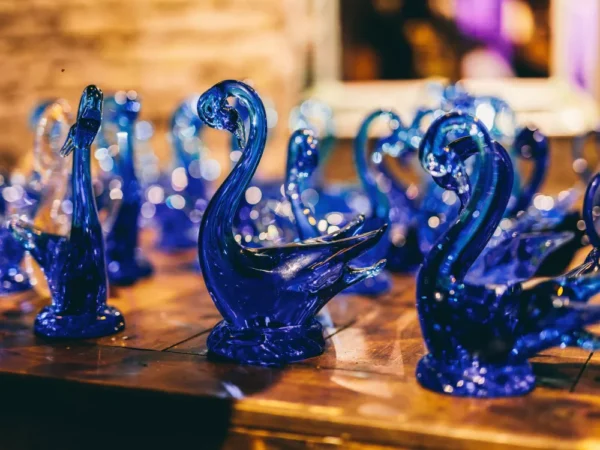 Set of two cobalt blue glass swan figurines with a sparkling, bubbly texture on a wooden surface.