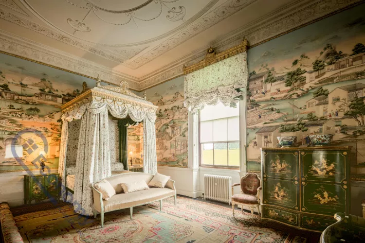 A magnificent bedroom showcasing chinoiserie decorating ideas with hand-painted scenic wallpaper featuring pagodas, palm trees, and figures.