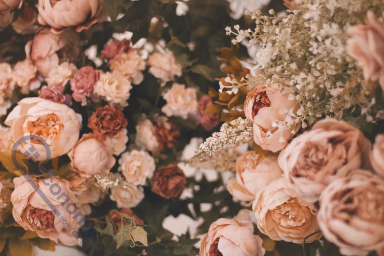 A beautiful, soft focus close-up of large, full-bloomed faux or dried roses and peonies in shades of dusty peach and pink.