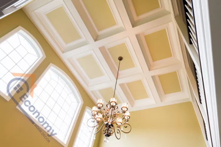 A traditional brass chandelier hanging from a coffered ceiling with alternating white and yellow painted panels.