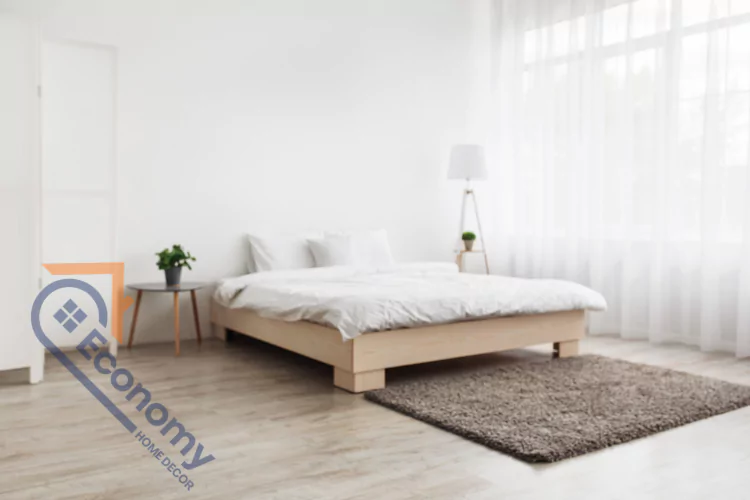A minimalist bedroom featuring white walls and white bedding on a light wood platform bed, creating a clean and airy space.