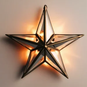 Illuminated 3D star wall sconce with antiqued brass metal frame and beveled glass panels, casting a warm orange glow.