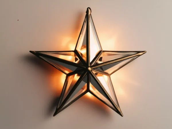 Illuminated 3D star wall sconce with antiqued brass metal frame and beveled glass panels, casting a warm orange glow.
