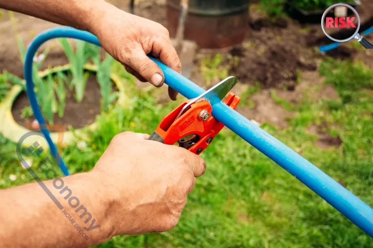 Hands cutting a blue drainage pipe outdoors, highlighting the risks of poor home drainage and the importance of proper maintenance.