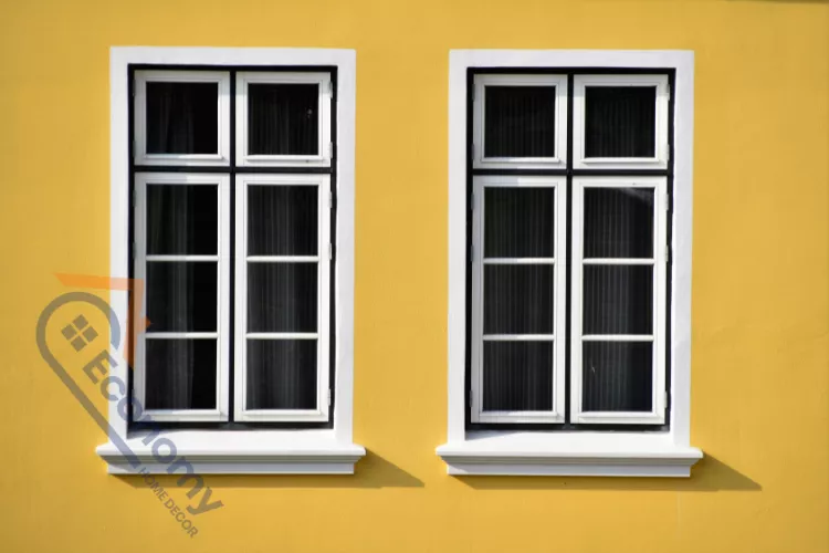 A classic white-framed window set against a light blue textured wall, serving as a canvas for exterior decorations.