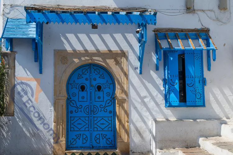 A beautiful front door fall decor idea with stacked pumpkins and large planters flanking a navy blue door.