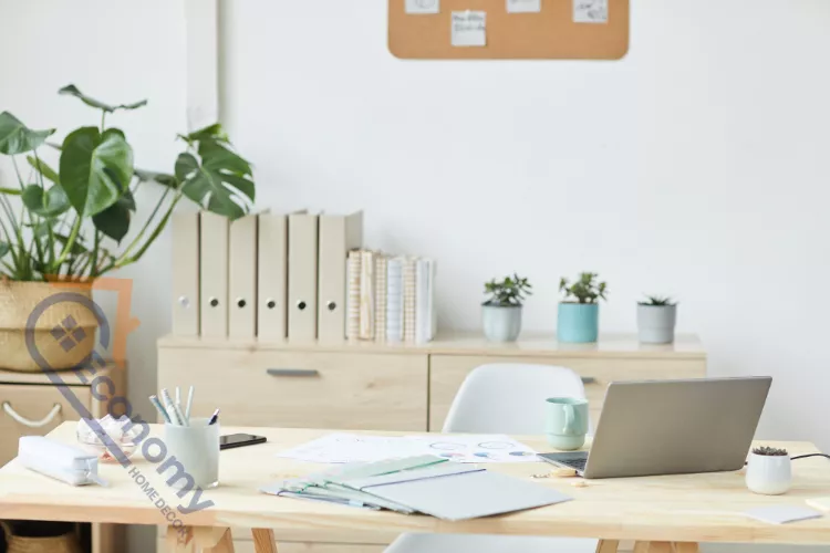 A minimalist white desk demonstrating office spring decorating ideas with a small blue ceramic vase and colorful notebooks.
