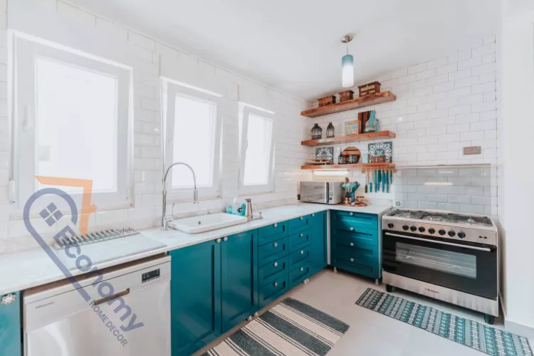 Modern kitchen with teal blue cabinets, white subway tile backsplash, open wooden shelves, stainless steel oven, and bright natural lighting