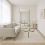 Bright narrow living room with light grey walls, floating sofa, and large mirror creating a spacious feel