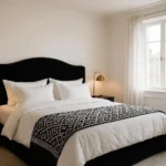 Black and white bedroom with upholstered headboard, layered bedding, and warm lighting