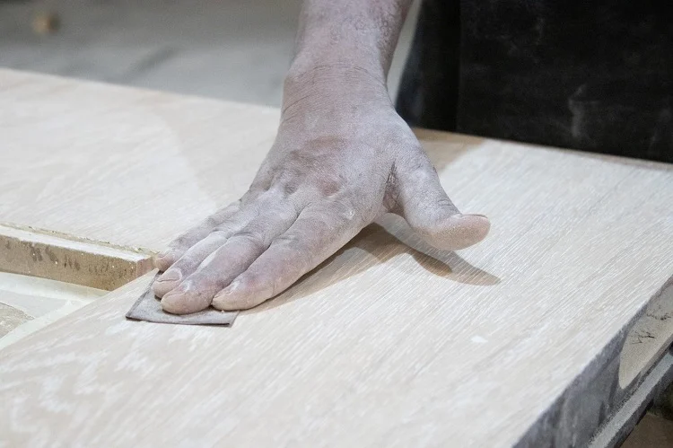 Hand-finishing a joinery panel at Spazio facility. The edge detail, surface texture, and finish quality are checked at every stage by the team responsible for the final installation. | Spazio Interior Decoration LLC